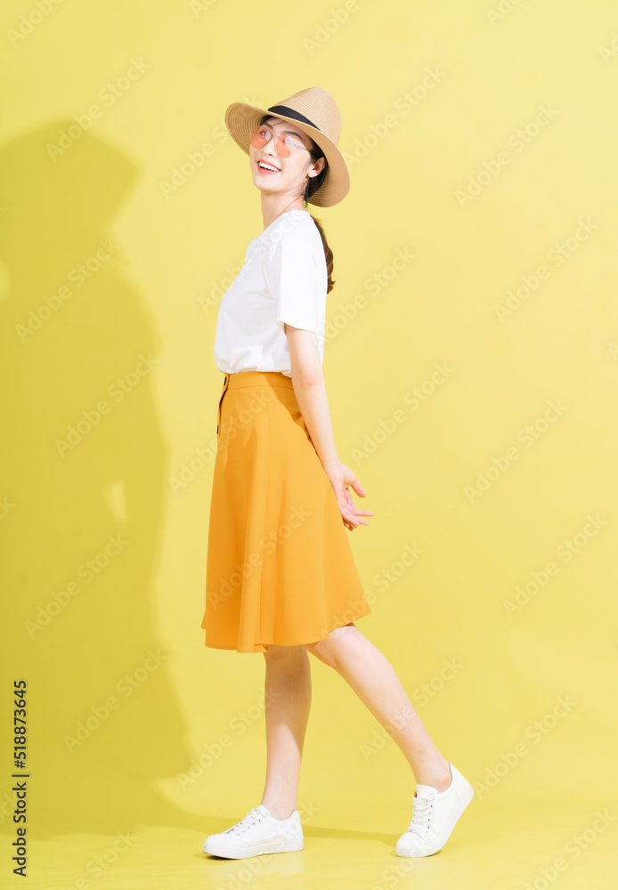 Full length photo of young Asian girl on yellow background