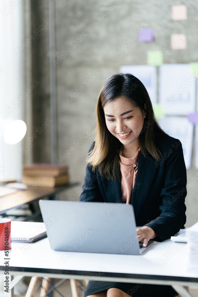 亚洲女性在办公室里用笔记本电脑工作。商业金融概念。