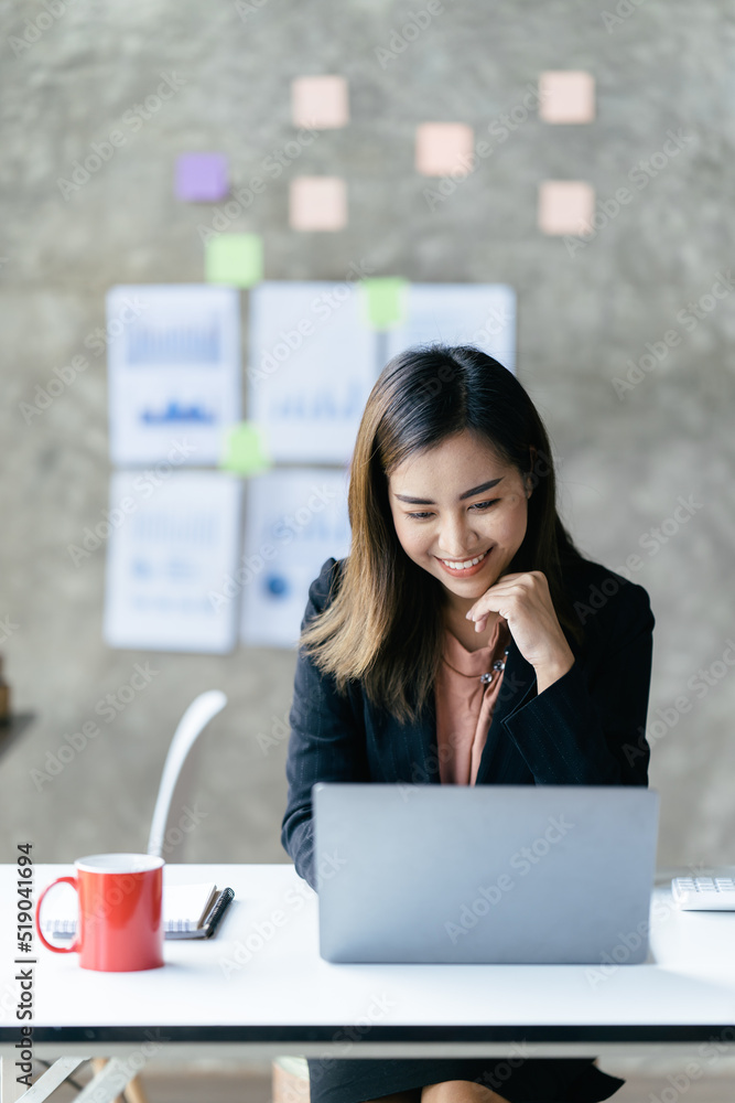 亚洲女性在办公室里用笔记本电脑工作。商业金融概念。