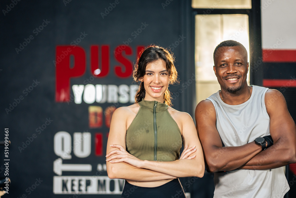 Portrait of athlete man and woman in sportswear crossing arms in gym.