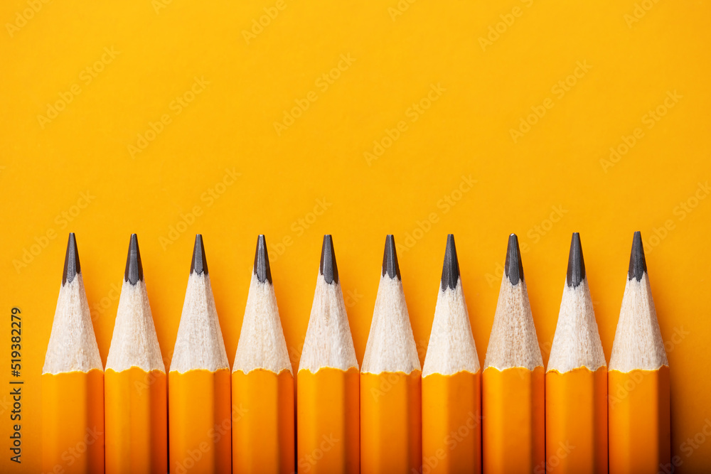 Abstract background of yellow pencils lying in a row. Yellow and orange colour concept