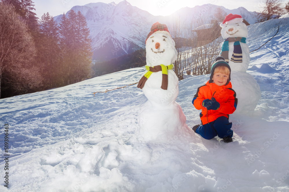 小男孩和雪人一起坐在雪地里翻山越岭