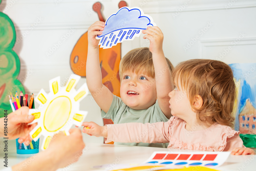 Boy, girl in the class play with weather rain and sun cards