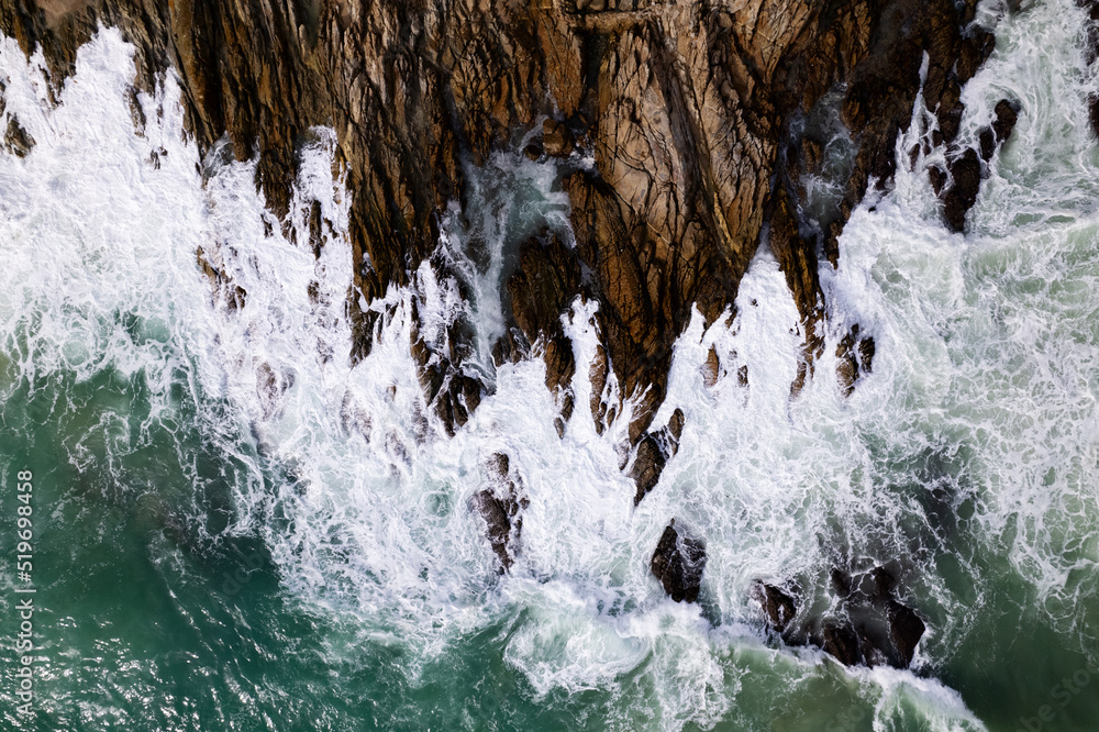 Aerial view Top down seashore big wave crashing on rock cliff Beautiful dark sea surface in sunny da