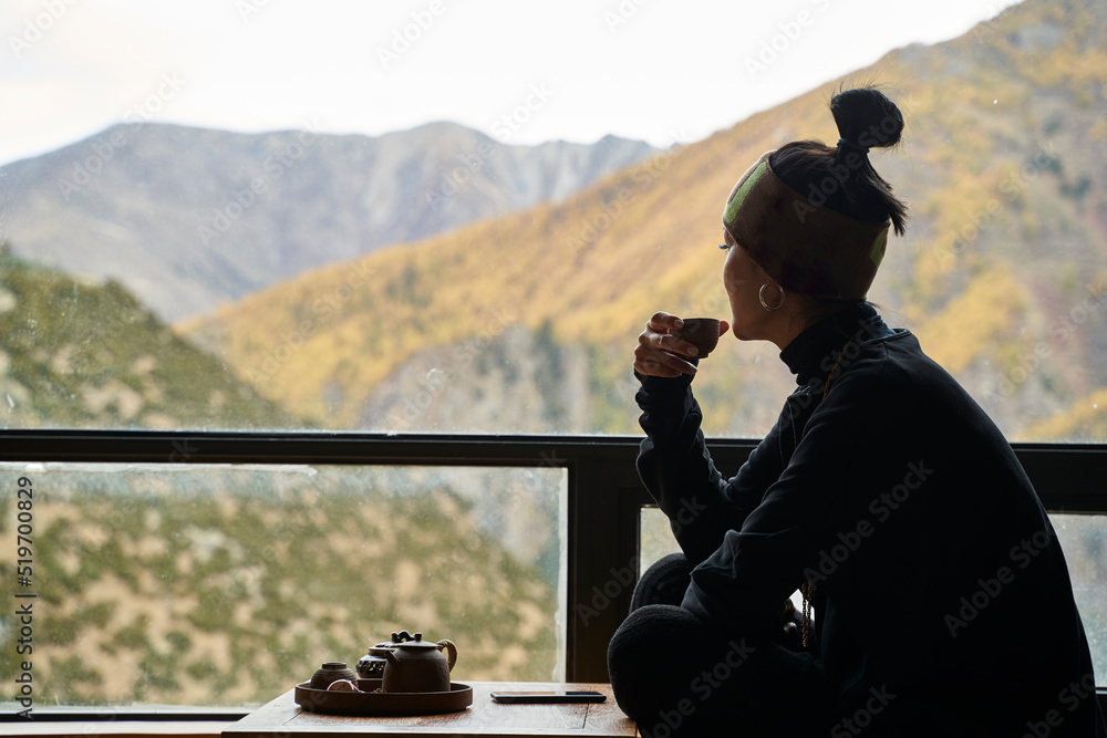 asian woman looking at view while enjoying a cup of tea on balcony