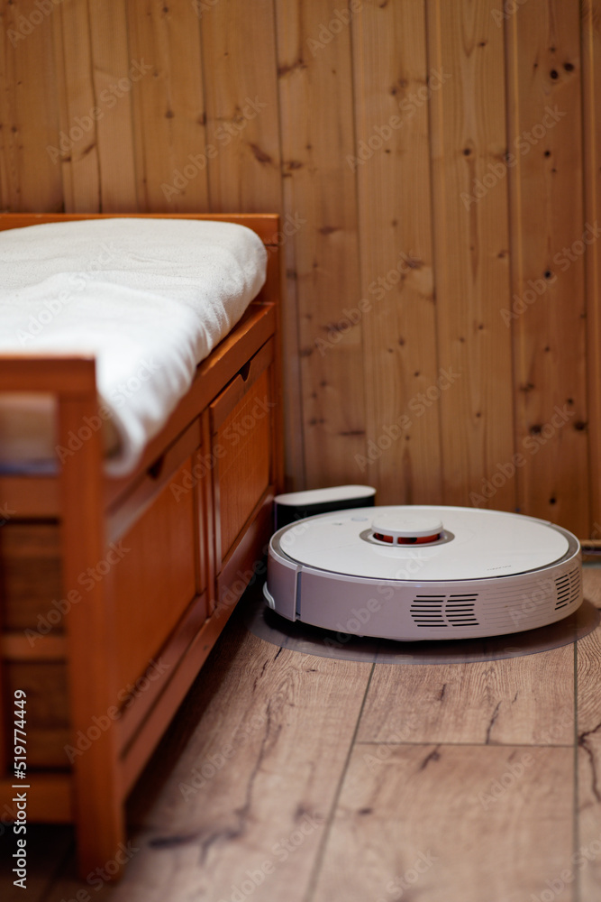 white mopping robot near wooden bench with white pillow