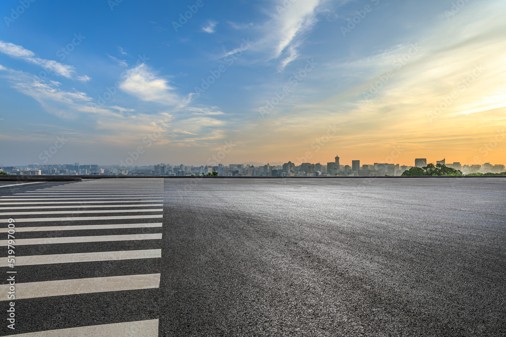 日出时天空乌云密布的沥青道路和城市天际线