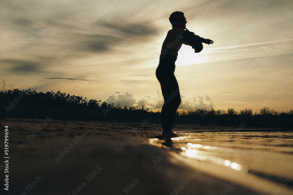 一名男性潜水员在海滩上穿上潜水服的剪影