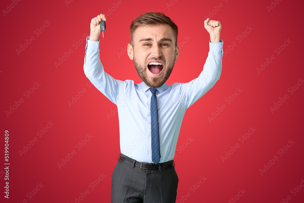 Happy funny businessman with big head holding car key on red background