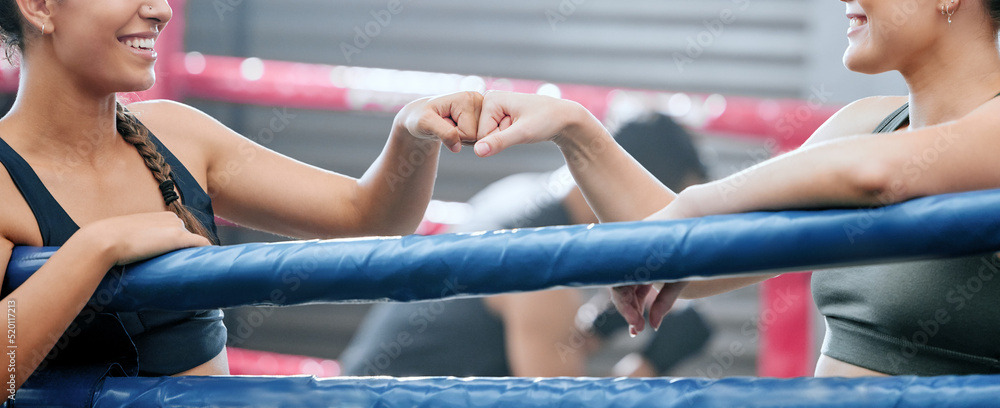 Closeup of happy women showing support, motivation and unity with fist bump at the gym or fitness cl