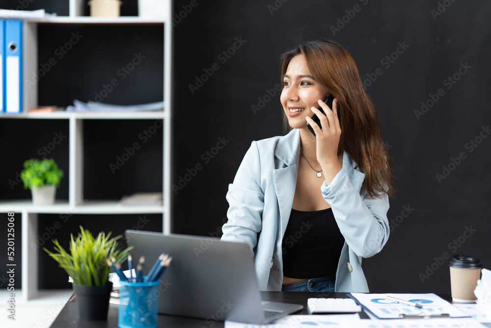 Asian businesswoman in formal suit in office happy and cheerful during using smartphone and working.