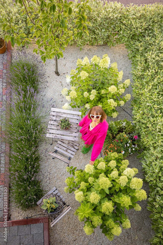 Woman at her beautiful tiny garden with green hedge, lavender and flowers