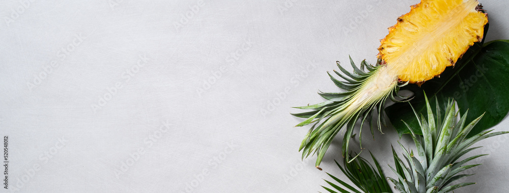 Fresh cut pineapple with tropical leaves on dark blue background.