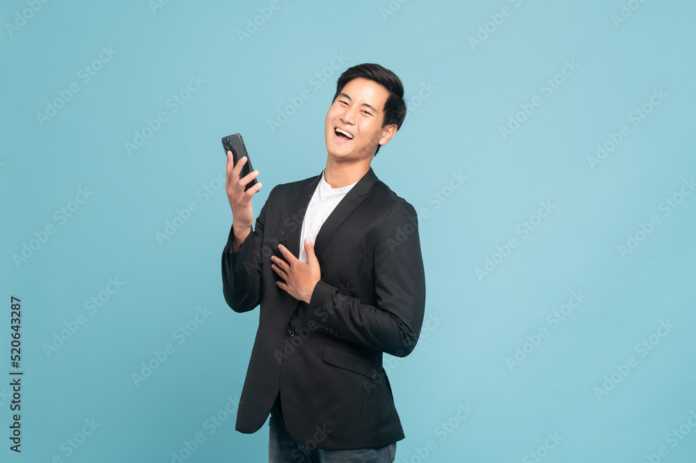 Young asian man in suit and jeans for smart casual business concept using smart phone isolated on bl