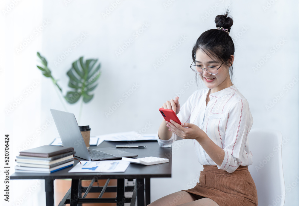 戴着眼镜的快乐迷人的女人在课堂上学习时微笑着用手机。