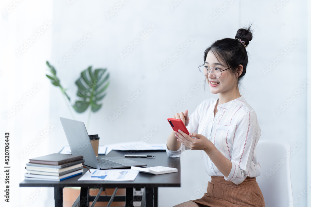 戴着眼镜的快乐迷人的女人在课堂上学习时微笑着用手机。