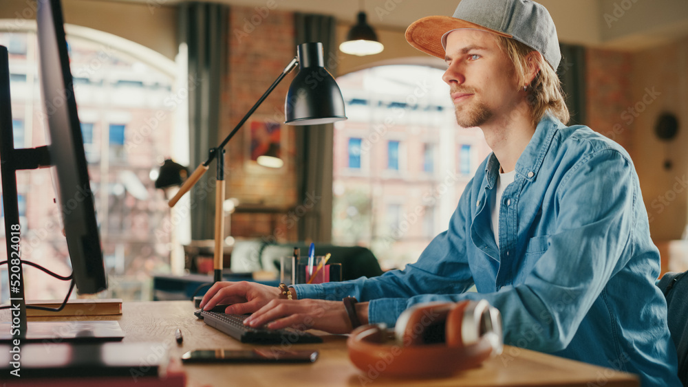 Young Handsome Adult Man Wearing a Cap, Working from Loft Apartment on Desktop Computer. Talented Ma