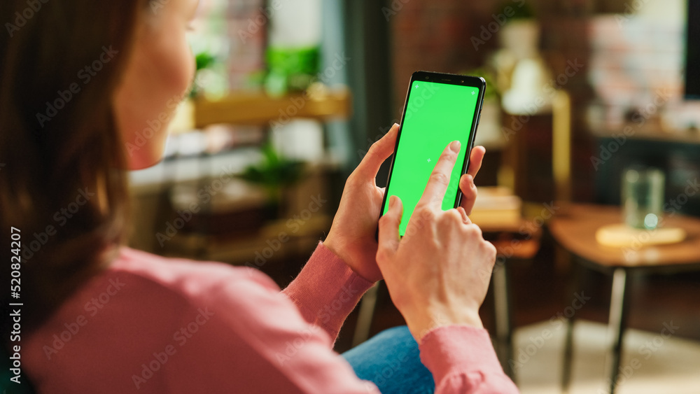 Feminine Hand Tapping on Display and Scrolling Feed on Smartphone with Green Screen Mock Up Display.