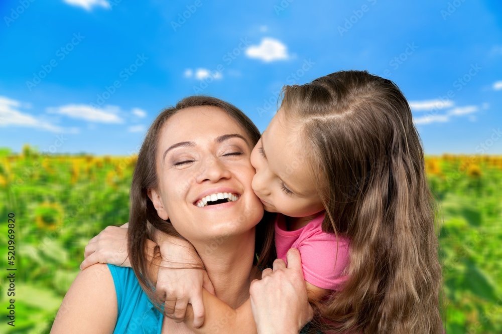 Tender mother and daughter happy together, hugging in nature in a field on a summer day