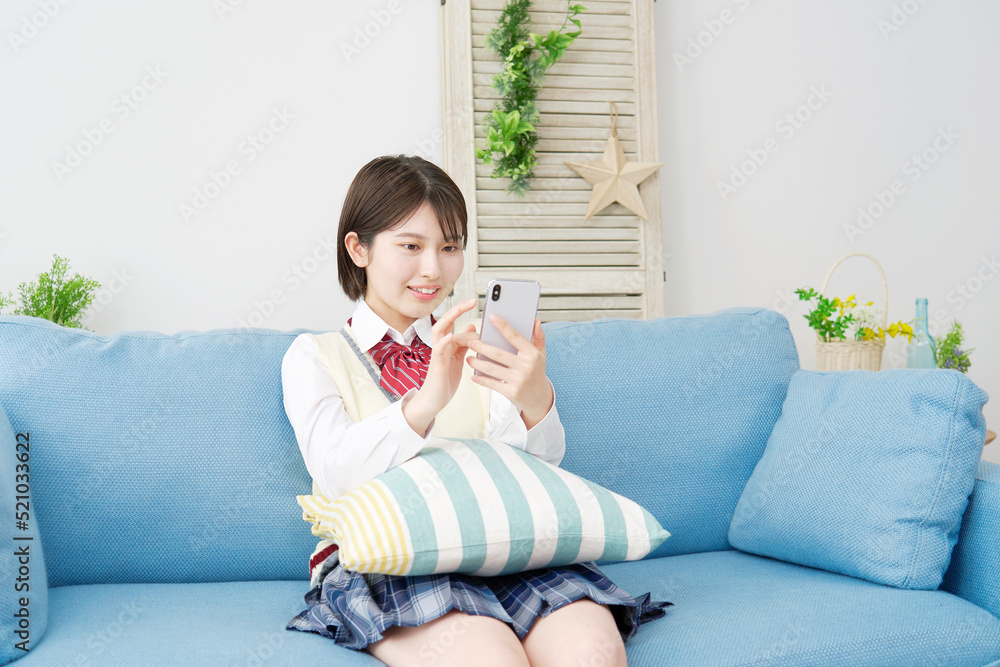 自宅でスマホを使う女子高生