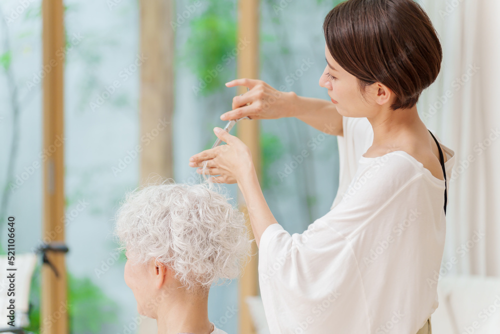 白髪の女性の髪を切る美容師