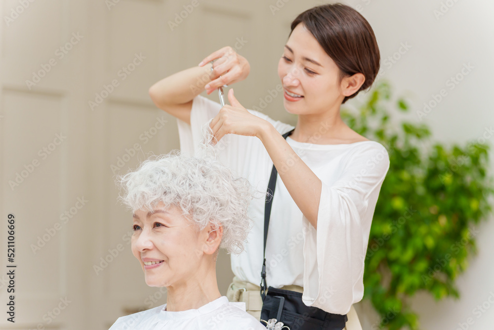 白髪の女性の髪を切る美容師