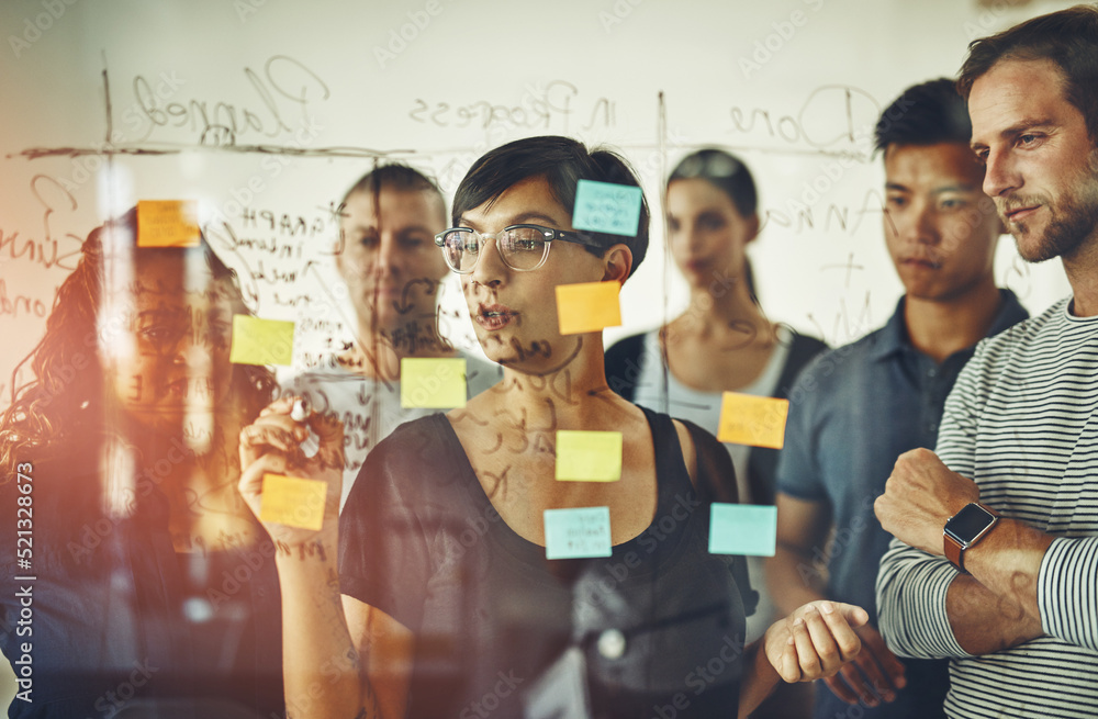 Business people planning ideas on a glass board thinking, brainstorming and working on strategy for 