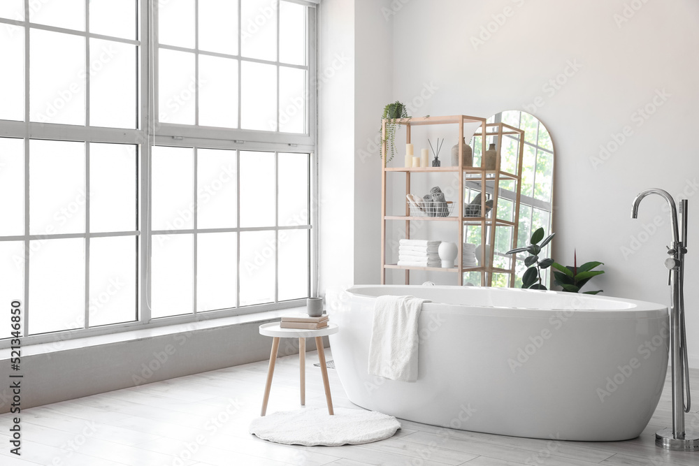 Interior of light bathroom with wooden shelving unit and mirror