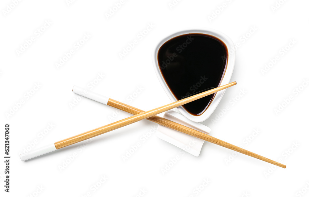 Bowl of soy sauce and chopsticks on white background