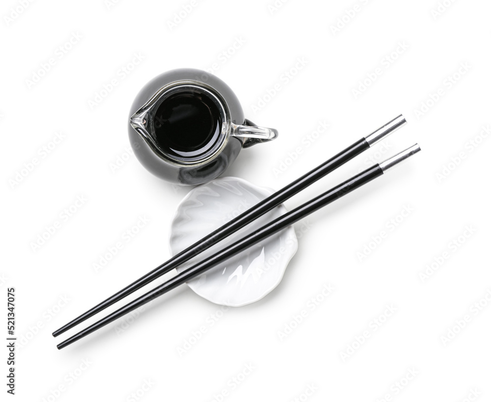 Jug of soy sauce and chopsticks on white background