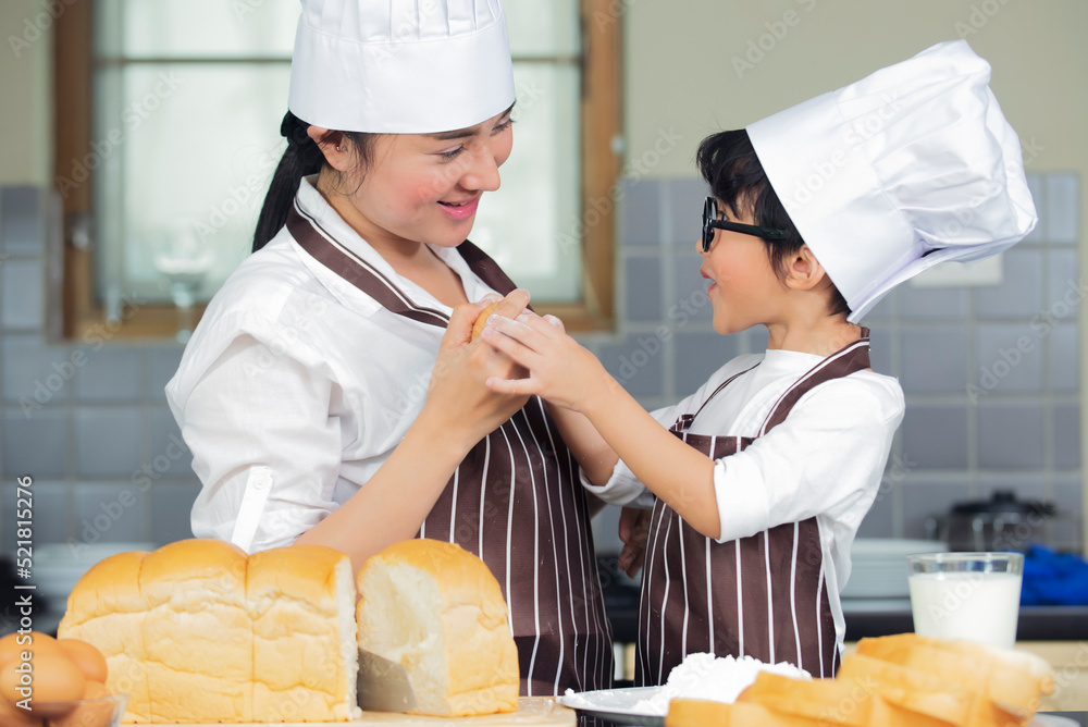 Cute asian boy with mother wearing chef hat  apron preparing for baking dough in kitchen at home