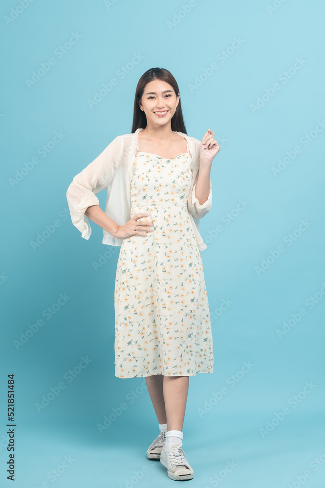 Beautiful young asian woman in white dress with flower pattern isolated on blue background