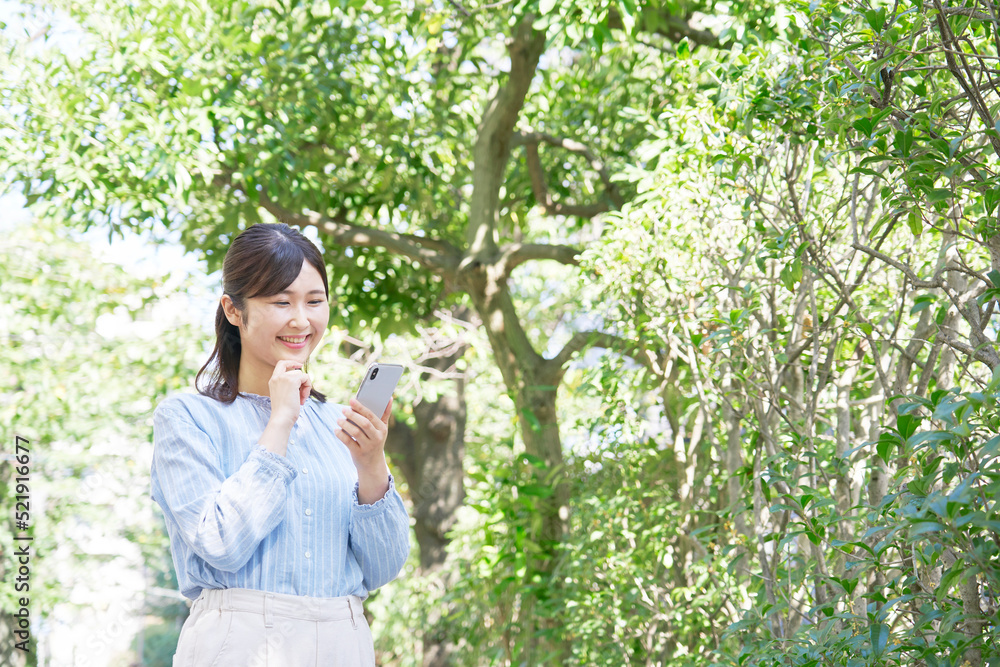 屋外で笑顔でスマホを使う女性