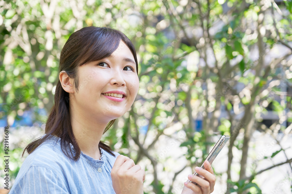 屋外で笑顔でスマホを使う女性