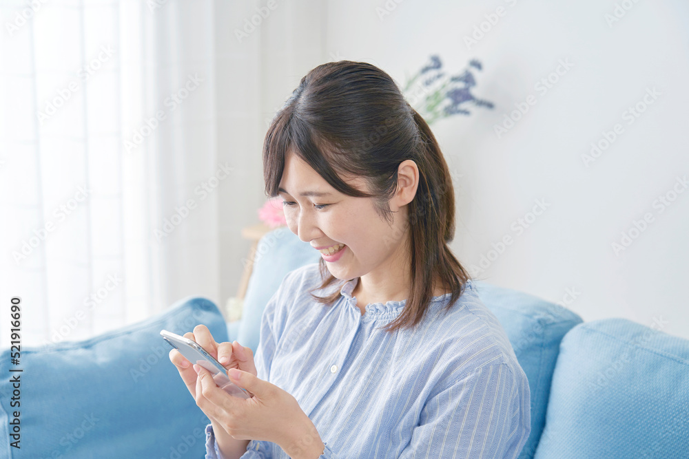 自宅でスマホを笑顔で使う女性