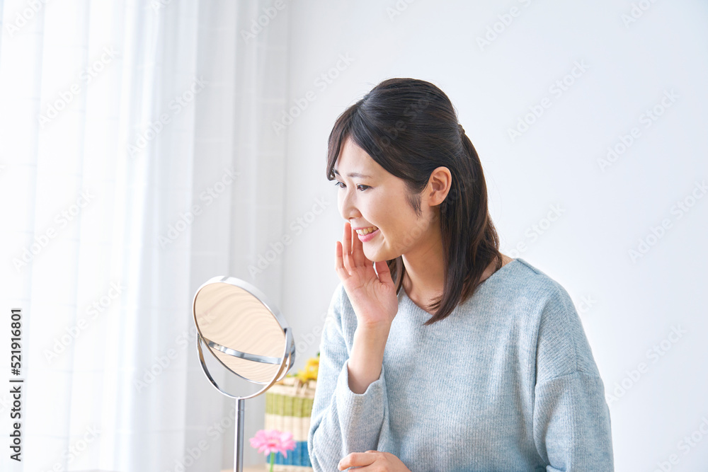 自宅で鏡を見てスキンケアする女性