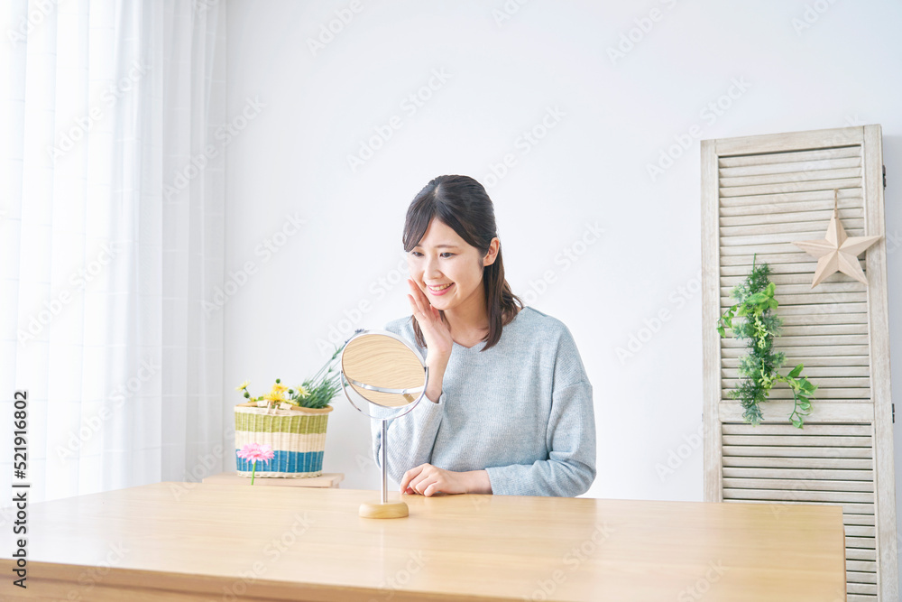 自宅で鏡を見てスキンケアする女性