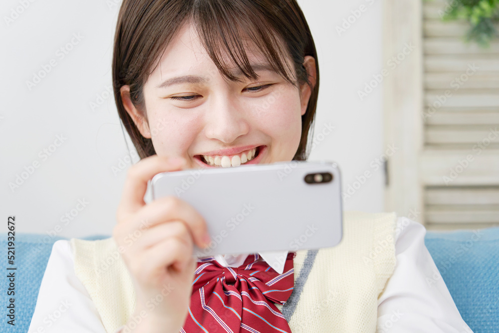 自宅でスマホで動画を見る女子高生