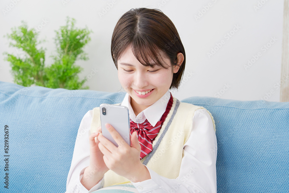 自宅でスマートフォンを使う女子高生