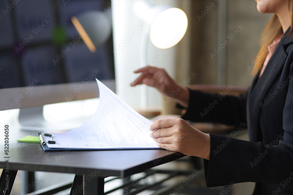 Businesswoman at her desk analyzing investment data on computer and planning business finances.