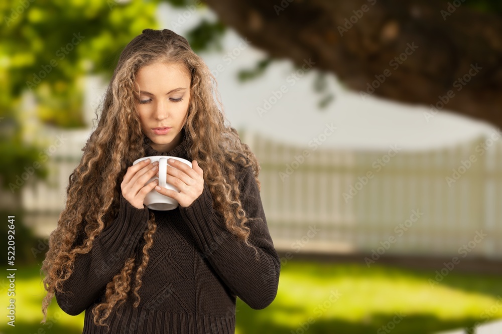 一位美丽的年轻女子喝着咖啡，在自然景观中放松的肖像图像