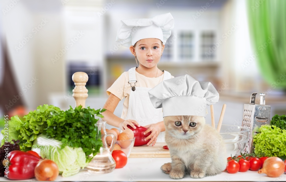 The cat chef sits at the kitchen table in a chefs hat with food.