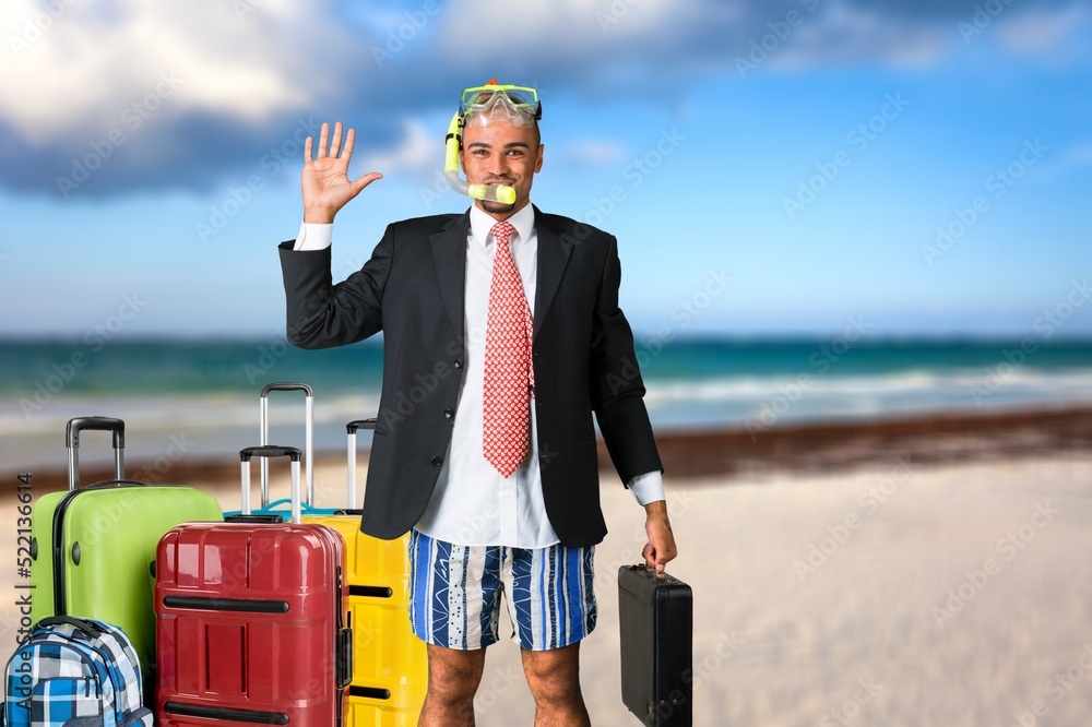 Happy funny young man standing with suitcase and getting ready to jump in sea waters