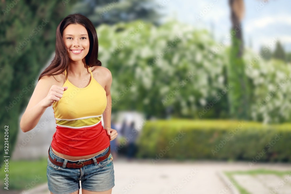 Smiling young woman in sportswear jogging at park on sunny day.