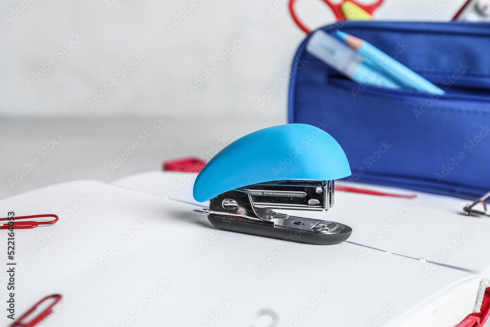 Stapler with stationery supplies on light background, closeup