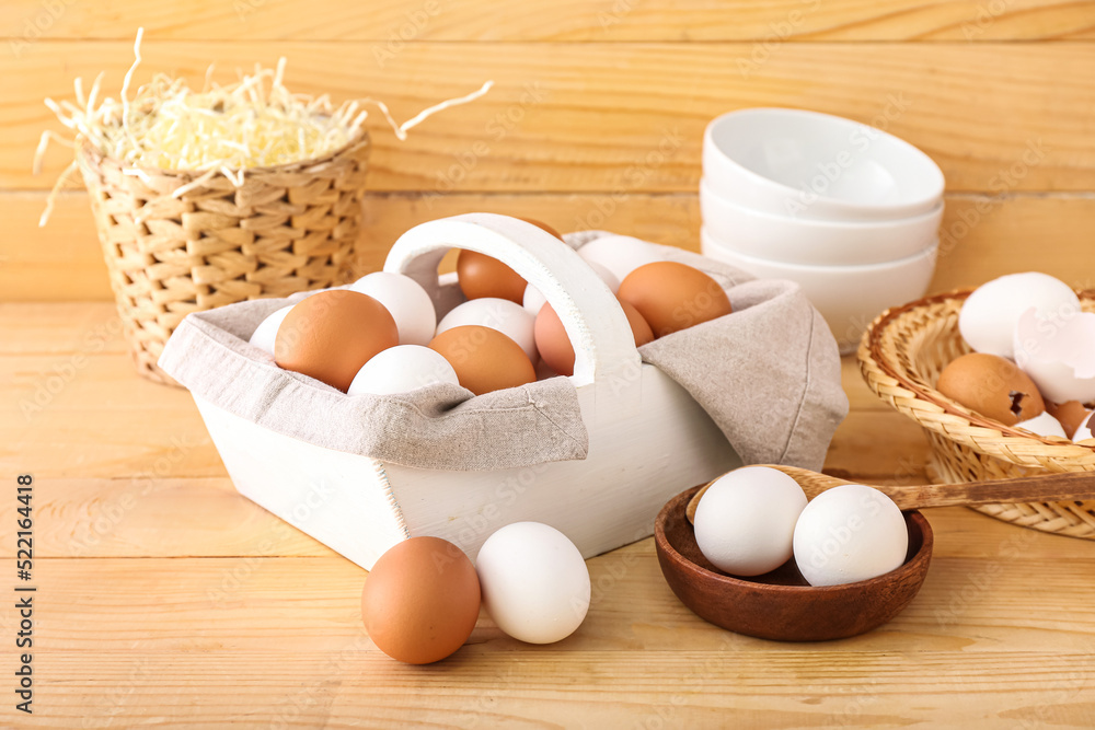 Basket with white and brown chicken eggs on wooden background