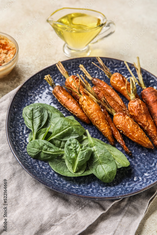 Plate of tasty baked carrots and spinach on light table, closeup