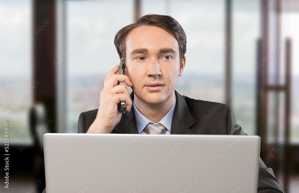 Young businessman using computer in office, thinking. Happy middle aged man, entrepreneur working on