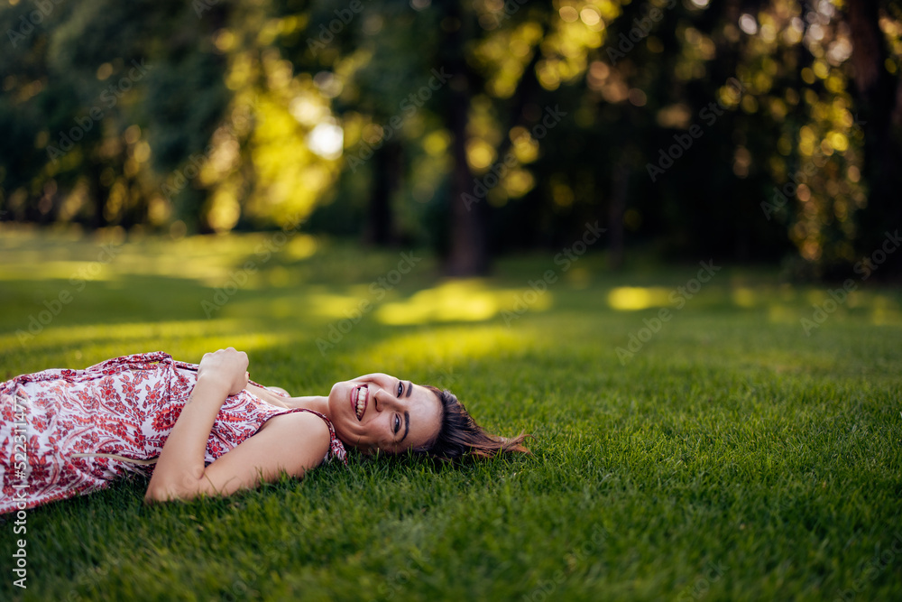 Smiling female, laying on the grass alone, smiling at the camera.