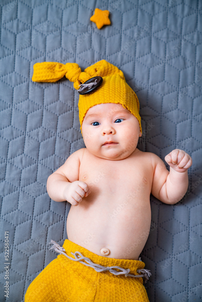 Cute newborn kid in yellow funny hat. Little sweet boy smilling.